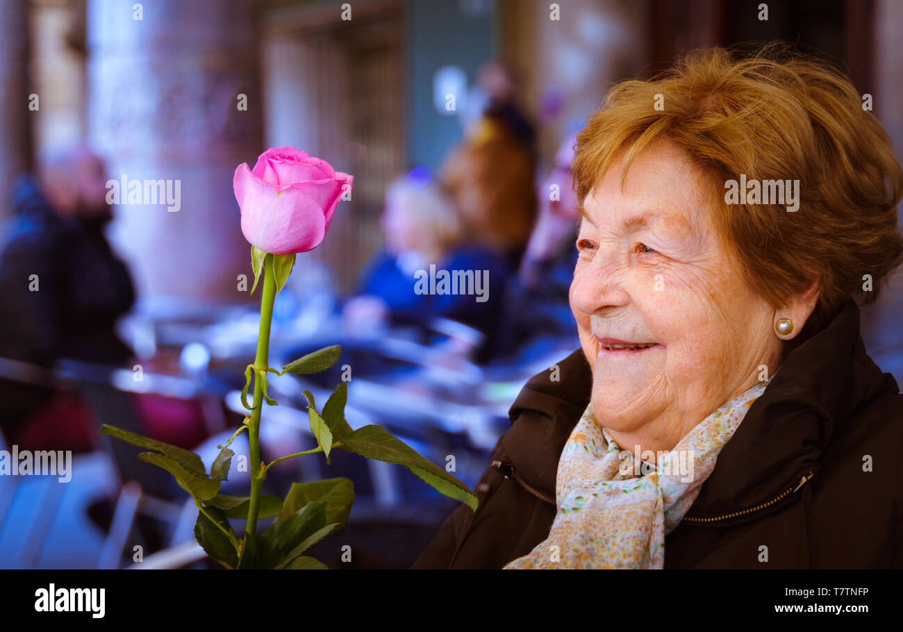 Smiling old woman with a pink rose Stock Photo