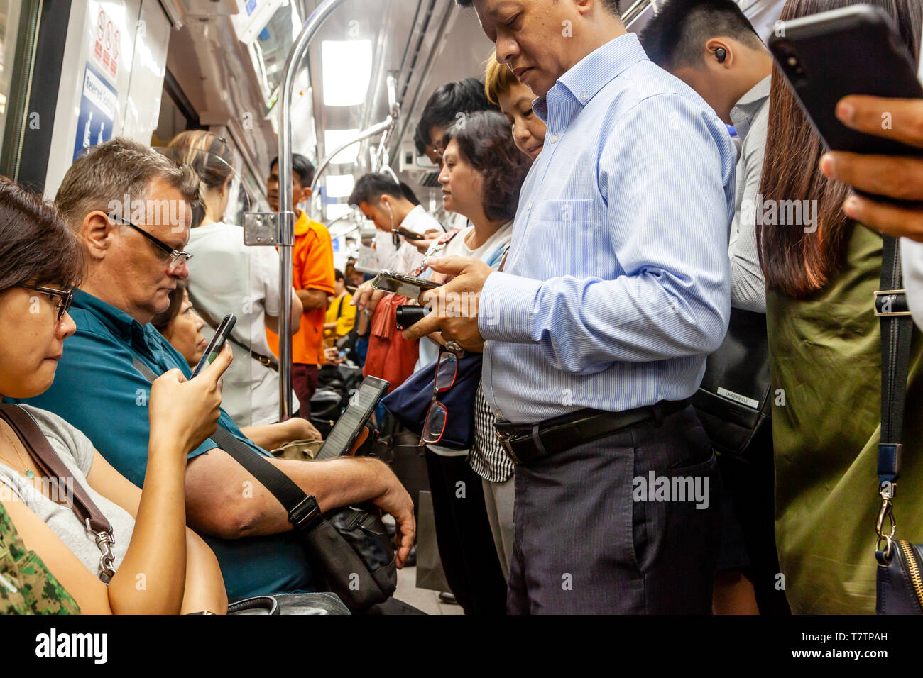 People Looking At Their Smartphones On The MRT, Singapore, South East Asia Stock Photo