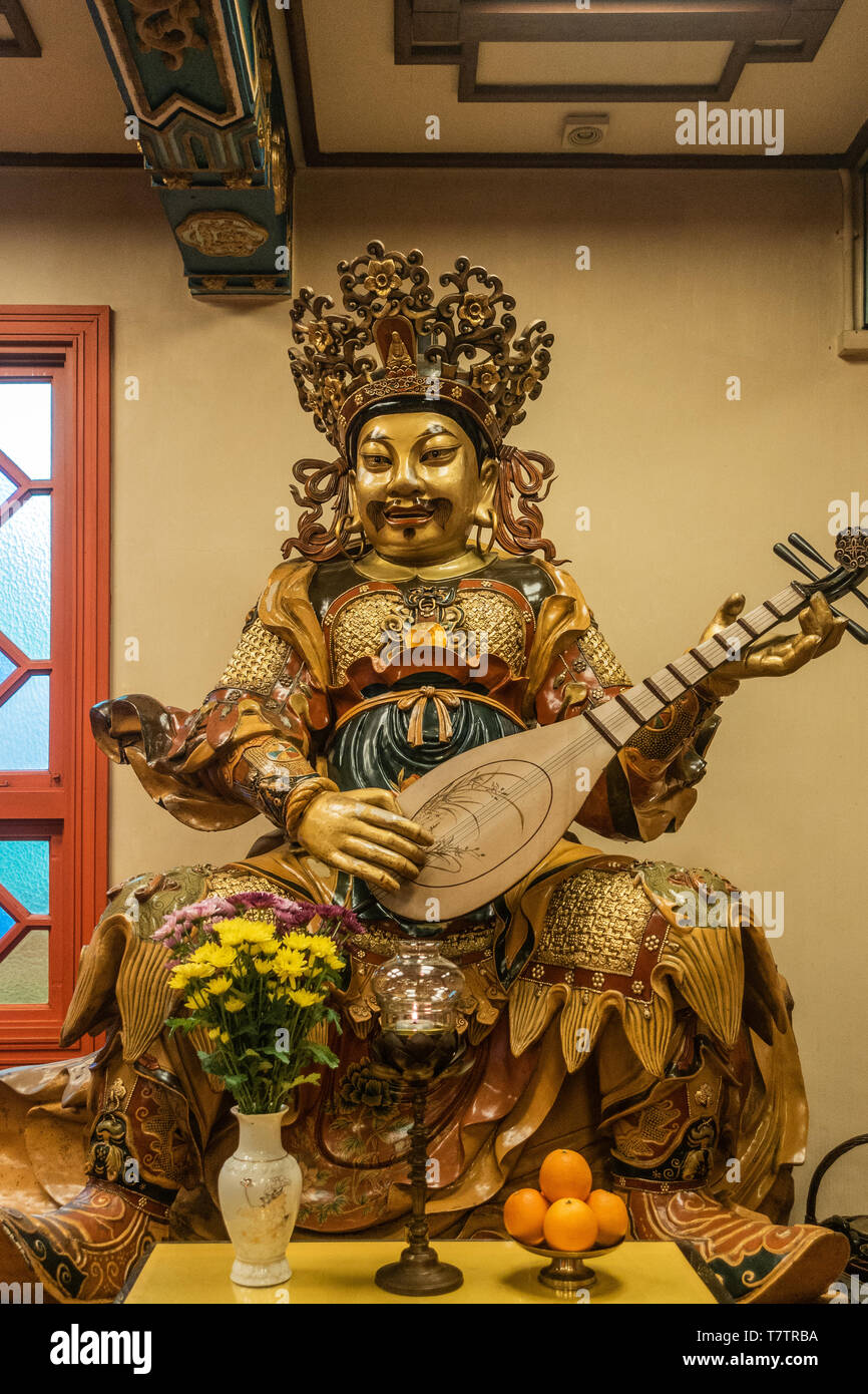 Hong Kong, China - March 7, 2019: Lantau Island. Po Lin Buddhist Monastery. Extensively decorated statue of East heavenly king Dhrtarastra offers shad Stock Photo