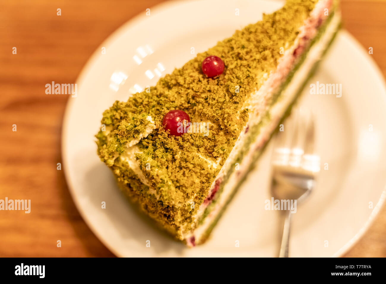 Healthy green spinach cake with white cheese cream and decorated with cranberries Stock Photo