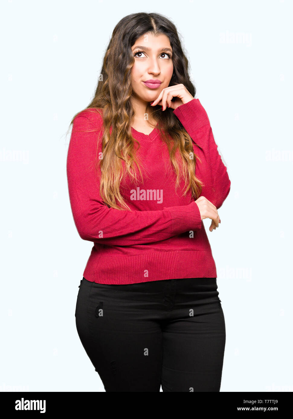Young beautiful woman wearing red sweater with hand on chin thinking about question, pensive expression. Smiling with thoughtful face. Doubt concept. Stock Photo