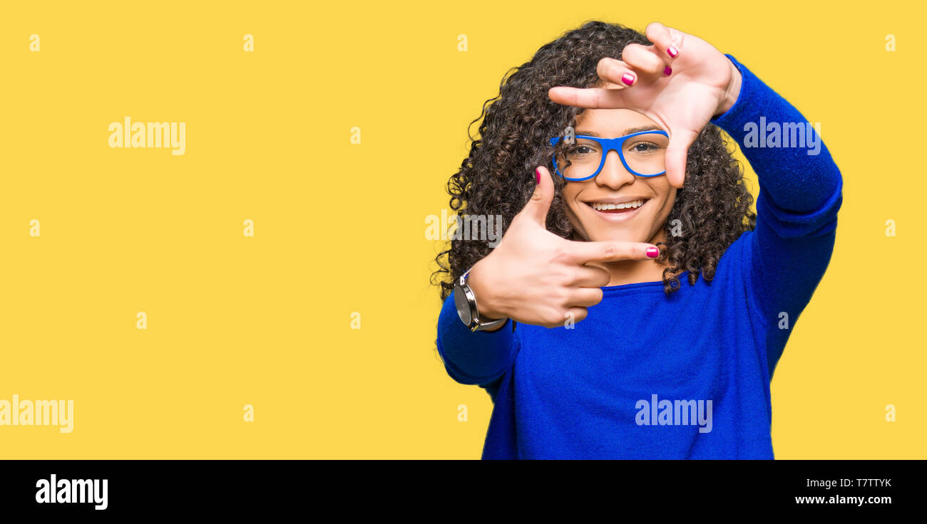Young beautiful woman with curly hair wearing glasses smiling making ...