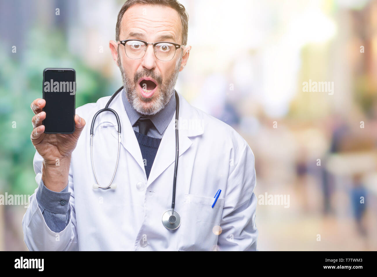 Middle age senior hoary doctor man showing smartphone screen over ...