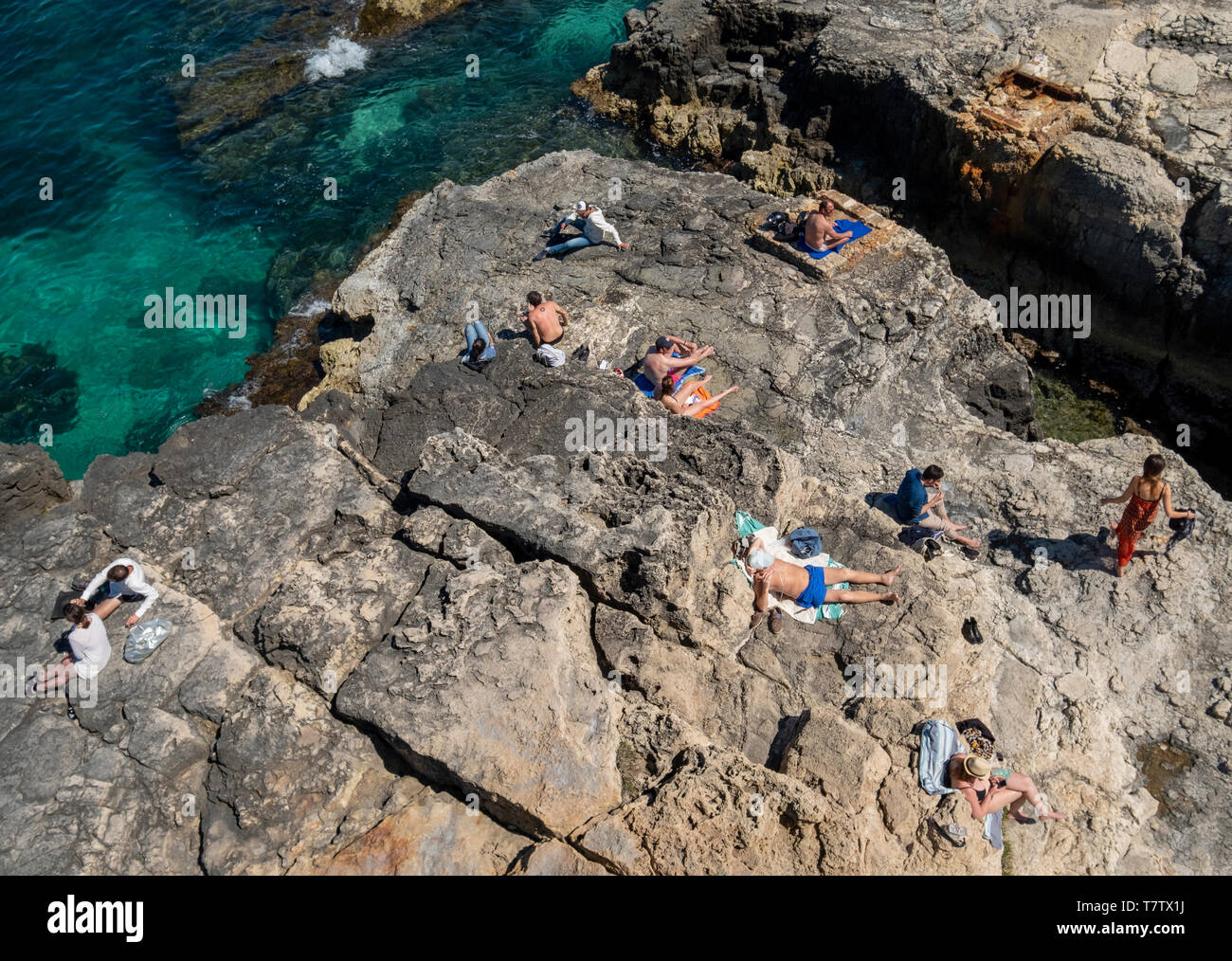People sunbathing on the rocky coastline, Ortygia Island, Syracuse, Sicily. Stock Photo