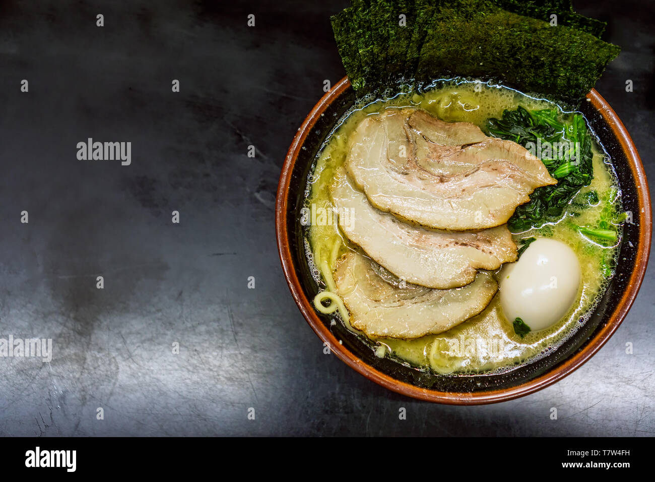 A hearty bowl of Ramen with pork, seaweed paper, and a boiled egg sits