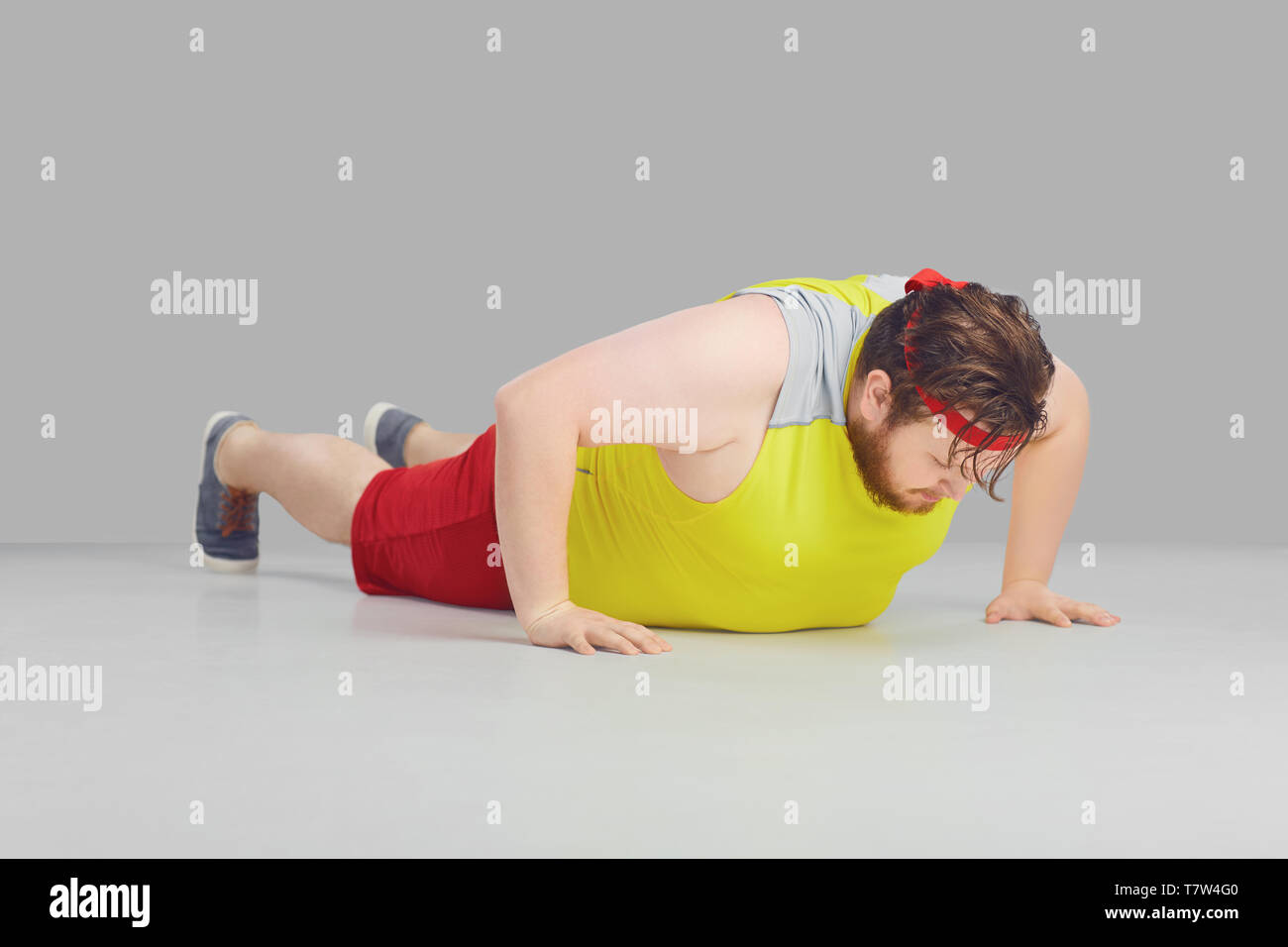 Fat funny guy with a beard doing push up goes for sports. Stock Photo