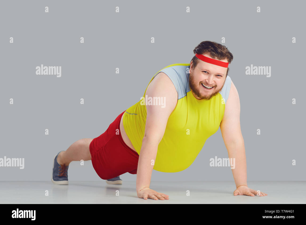 Fat funny guy with a beard doing push up goes for sports. Stock Photo