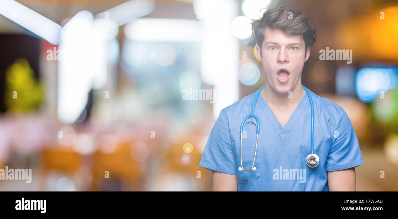 Young doctor wearing medical uniform over isolated background afraid ...