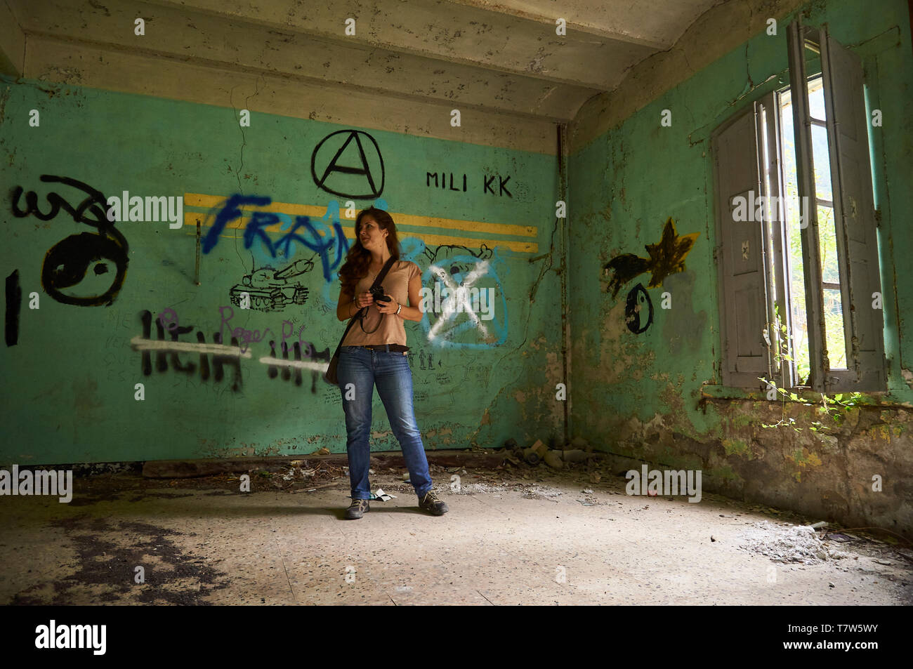 Female photographer in the interior of ruined facilities covered by graffiti at  the Canfranc International railway station (Huesca, Aragon, Spain) Stock Photo
