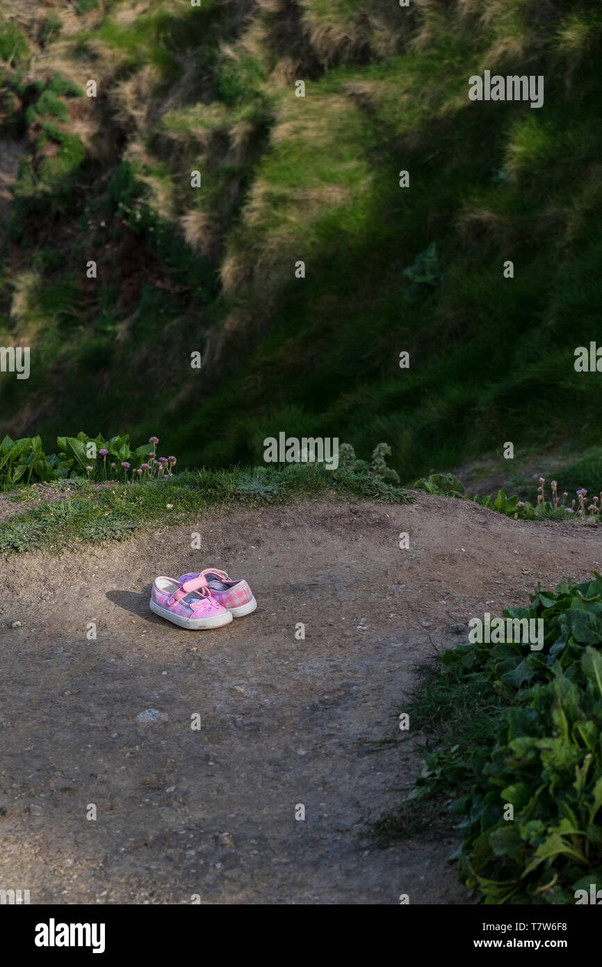 A pair of childrens pink sandals left on a path. Stock Photo