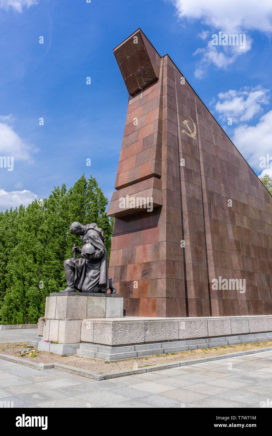 Statue of a kneeling Soviet soldier in front of a stylized Soviet flag built of red granite at the Soviet War Memorial in Berlin Treptow, Berlin Stock Photo