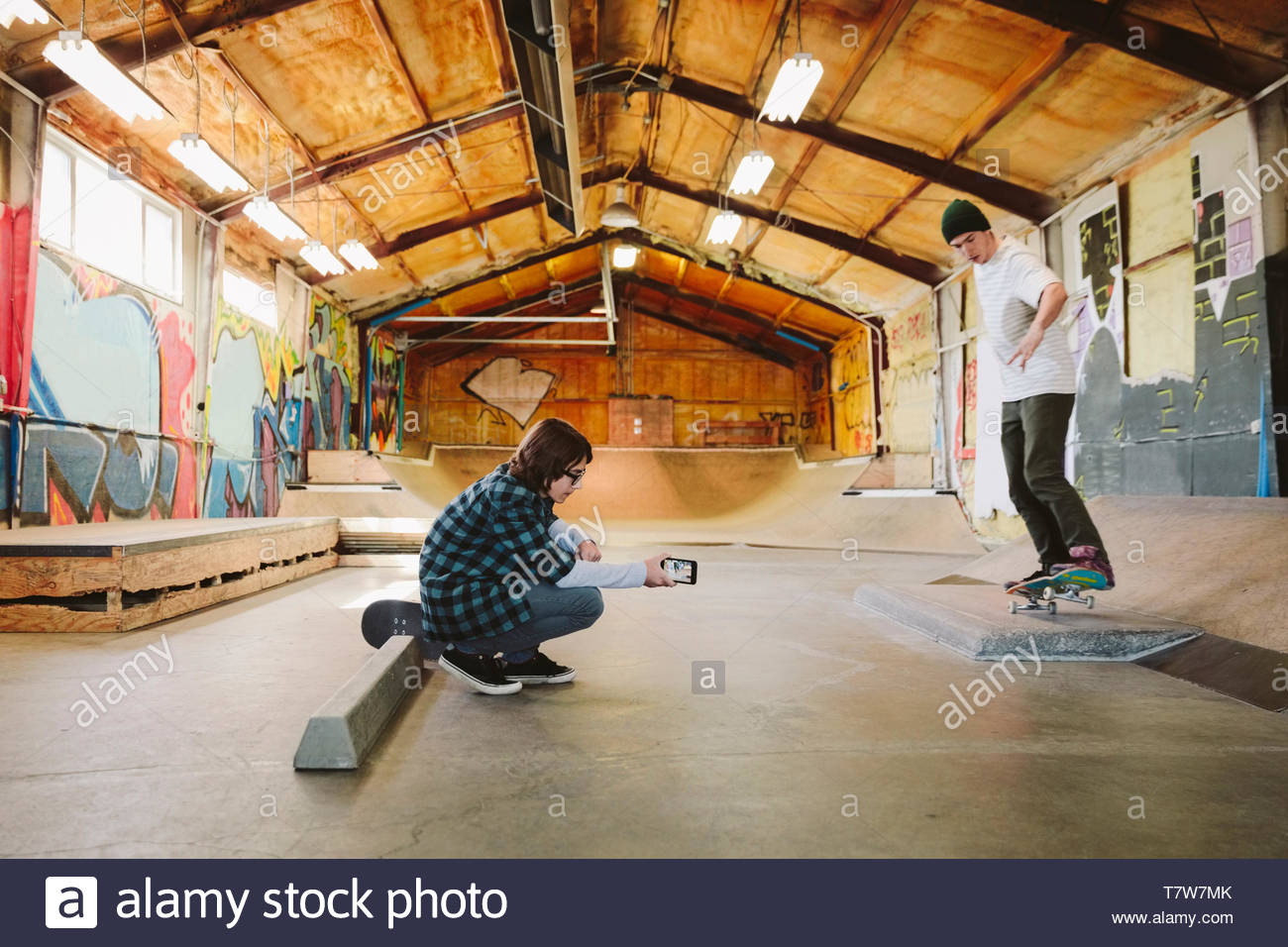 Teenage Boy With Camera Phone Filming Friend Skateboarding At