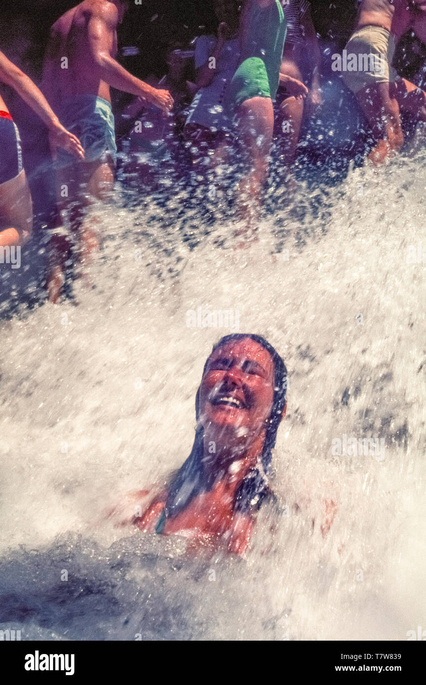 A suntanned woman enjoys a natural massage in the powerful splashing
