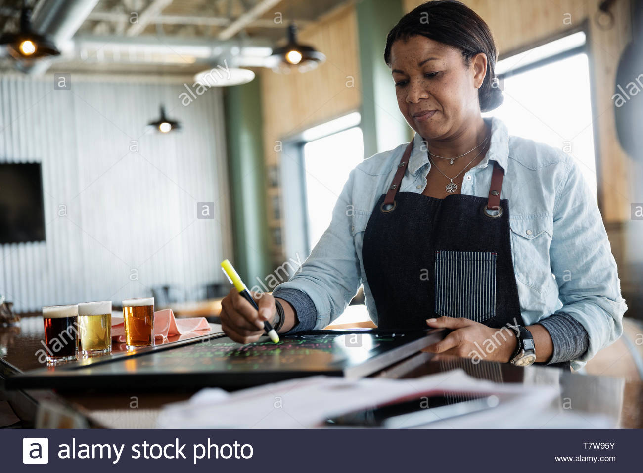 Female business owner writing on menu board in brewhouse Stock Photo