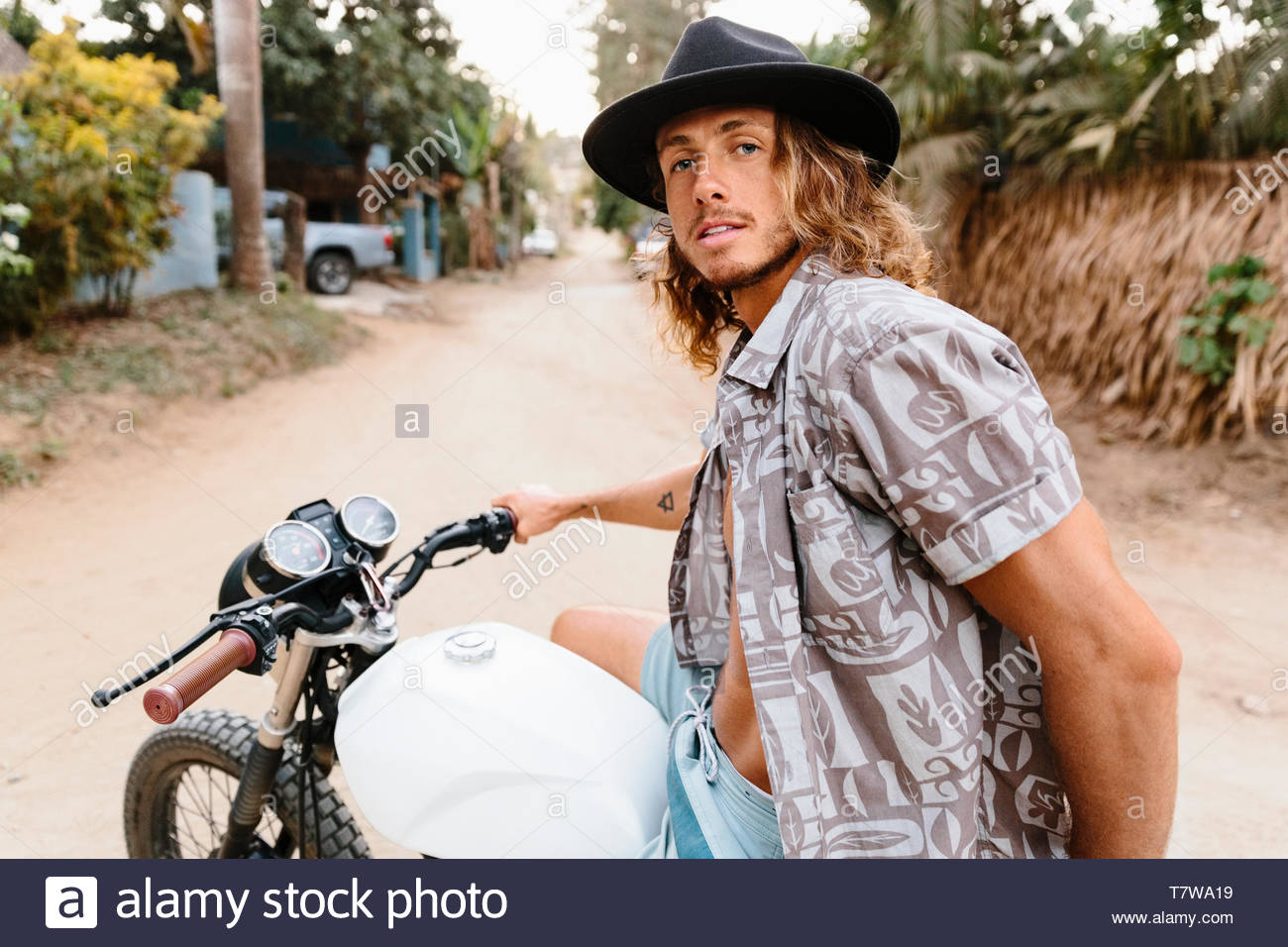 Portrait confident, cool young man riding motorcycle on dirt road, Mexico Stock Photo