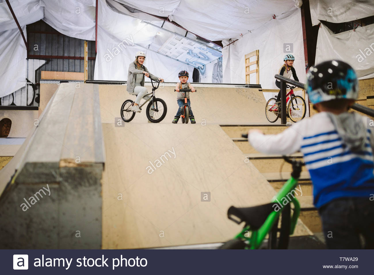 Family riding bmx bikes on ramps at indoor skate park Stock Photo Alamy