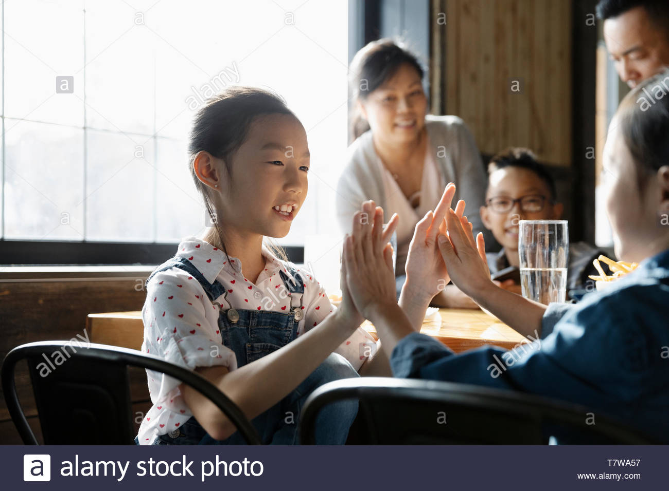 Sisters playing clapping game in restaurant Stock Photo