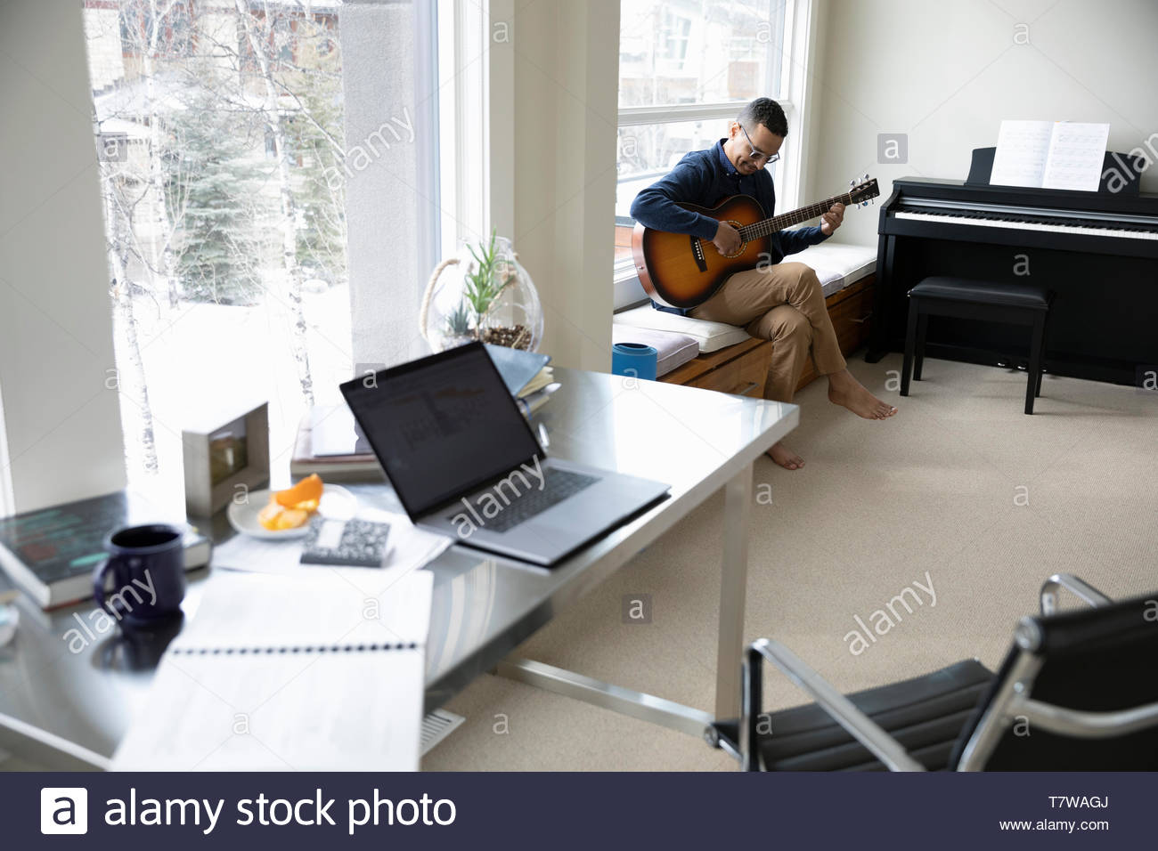 Man taking a break from working at home, playing guitar in home office Stock Photo