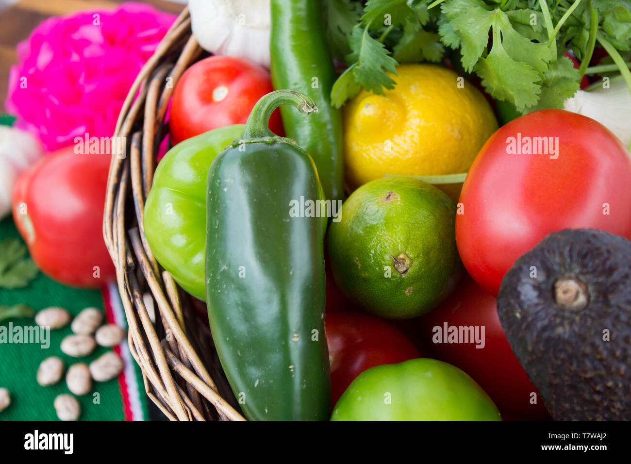 Close-up of wicker basket with fresh colorful ingredients for salsa on green sarape/Mexican blanket Stock Photo