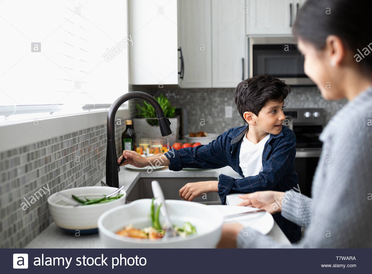 Brother and sister doing dishes at kitchen sink Stock Photo