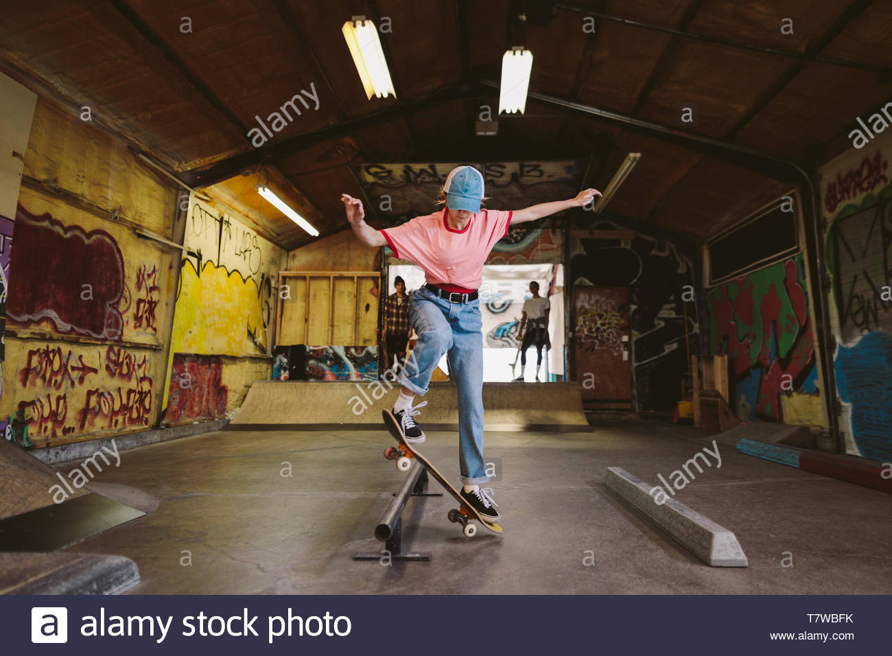 Woman skateboarding, sliding on rail at indoor skate park Stock Photo