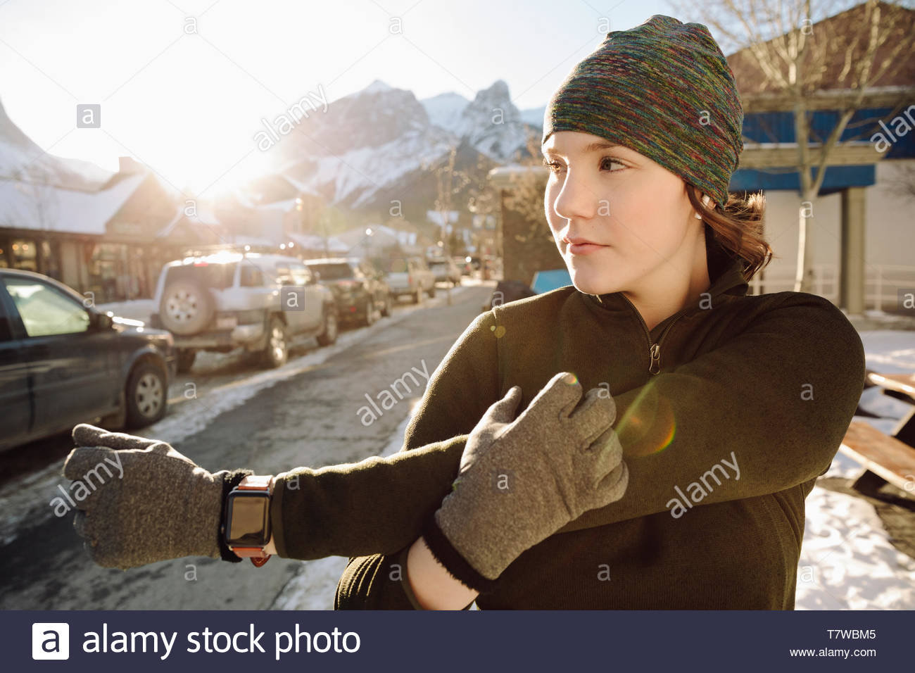 Teenage girl runner stretching arm on winter sidewalk Stock Photo
