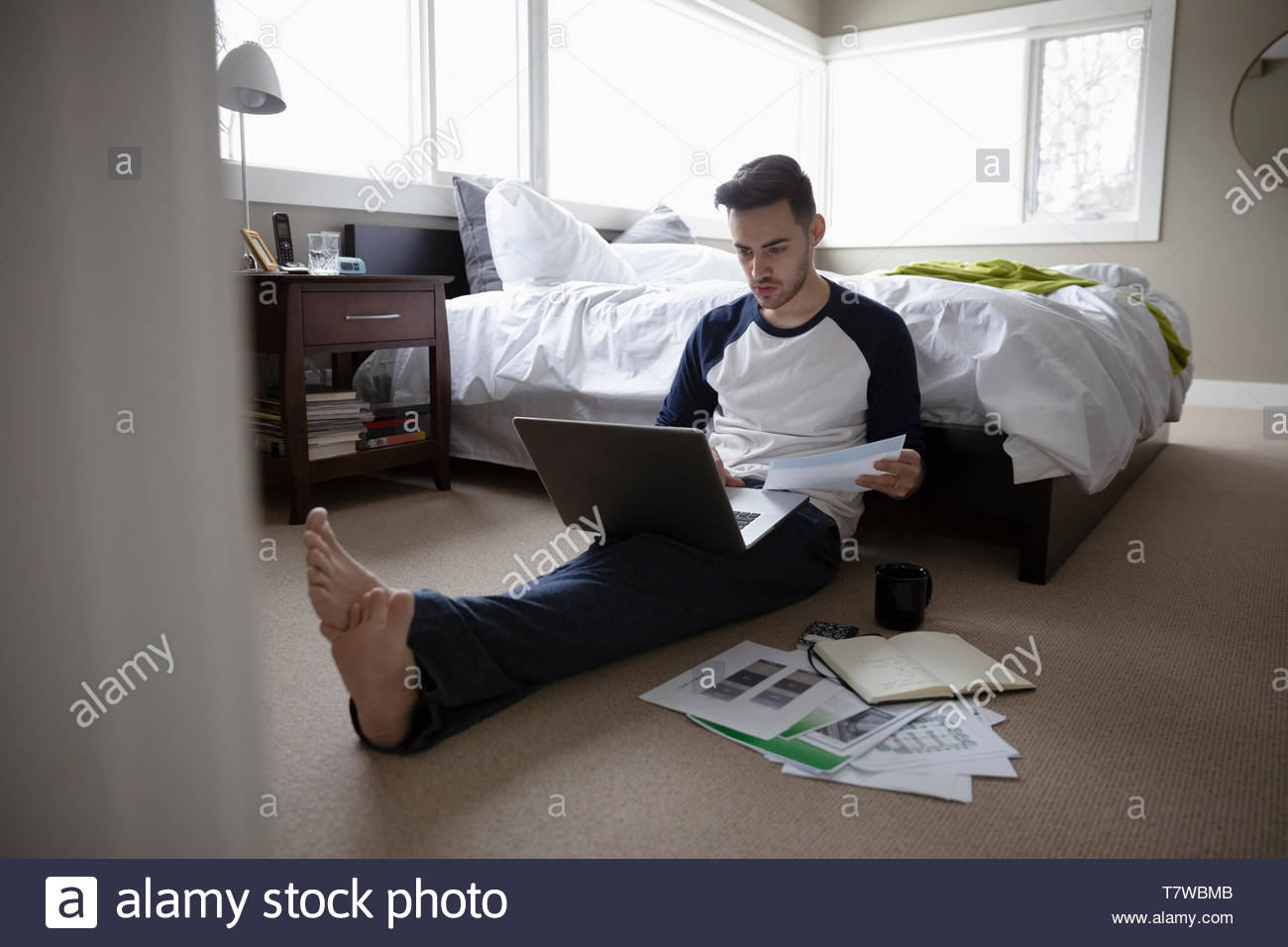 Young Man Working From Home Using Laptop On Bedroom Floor