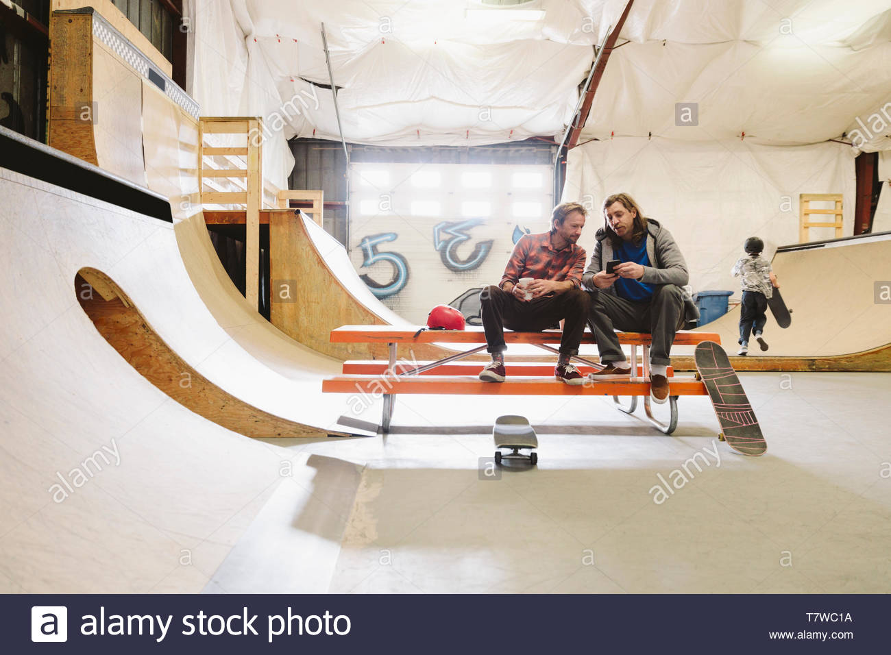 Mature men at indoor skate park, using smart phone Stock Photo