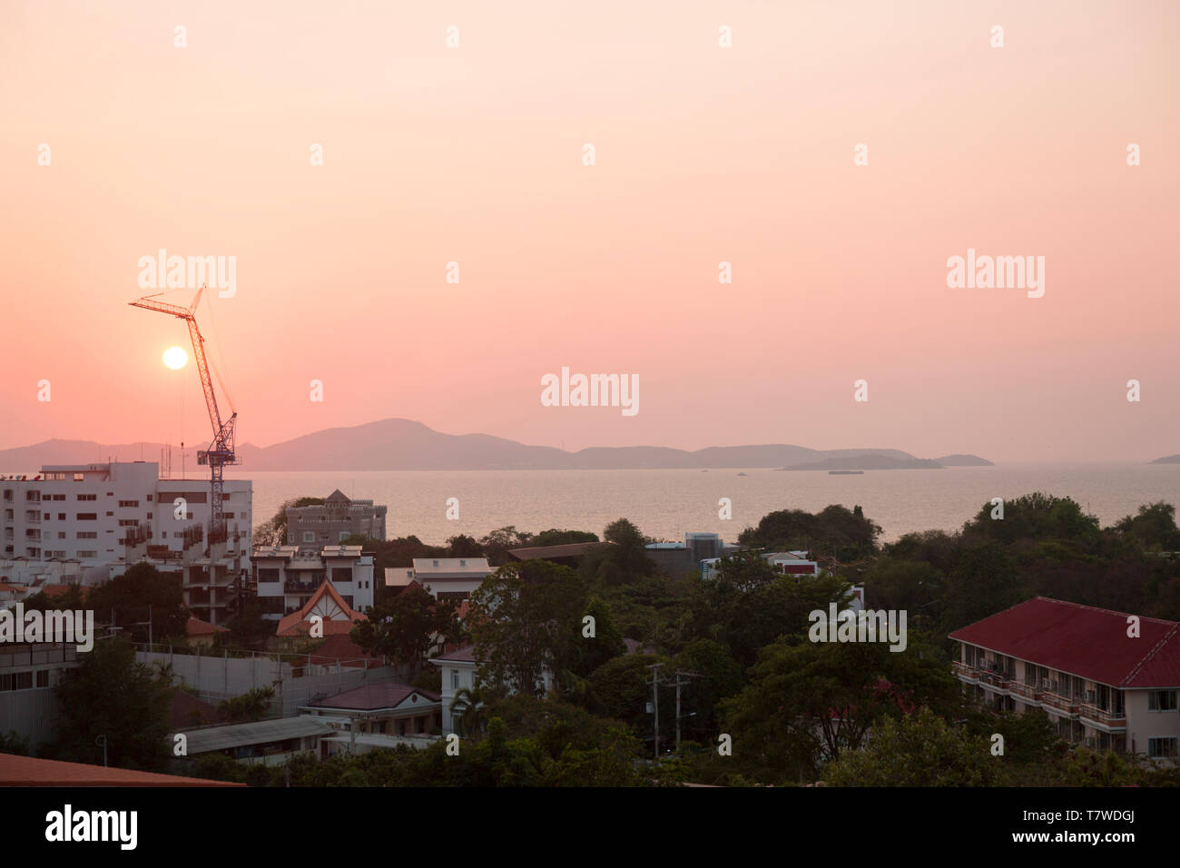 Building on the sea cost. Construction equipment at pink sunset. Real estate on the beach. Stock Photo