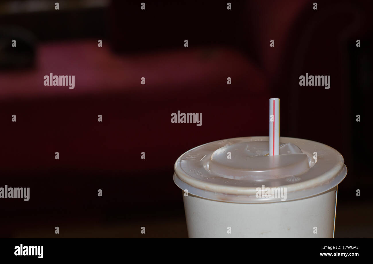 Plastic fast food lid and a plastic straw isolated against a dark out of focus background image