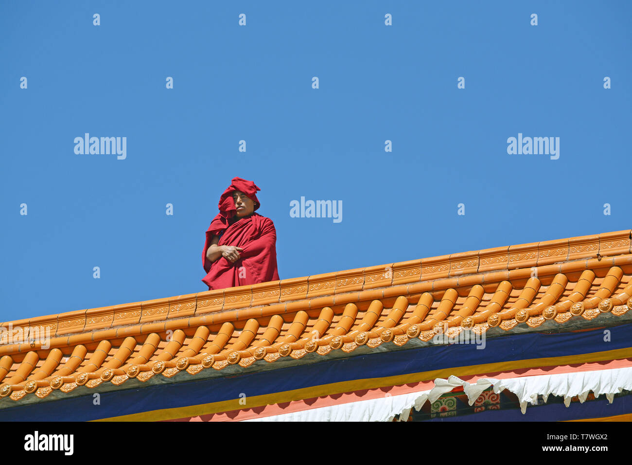View of a single Tibetan monk standing on the roof of a temple in the Lbrang monastery in Xiahe, Gansu Province, China. Stock Photo