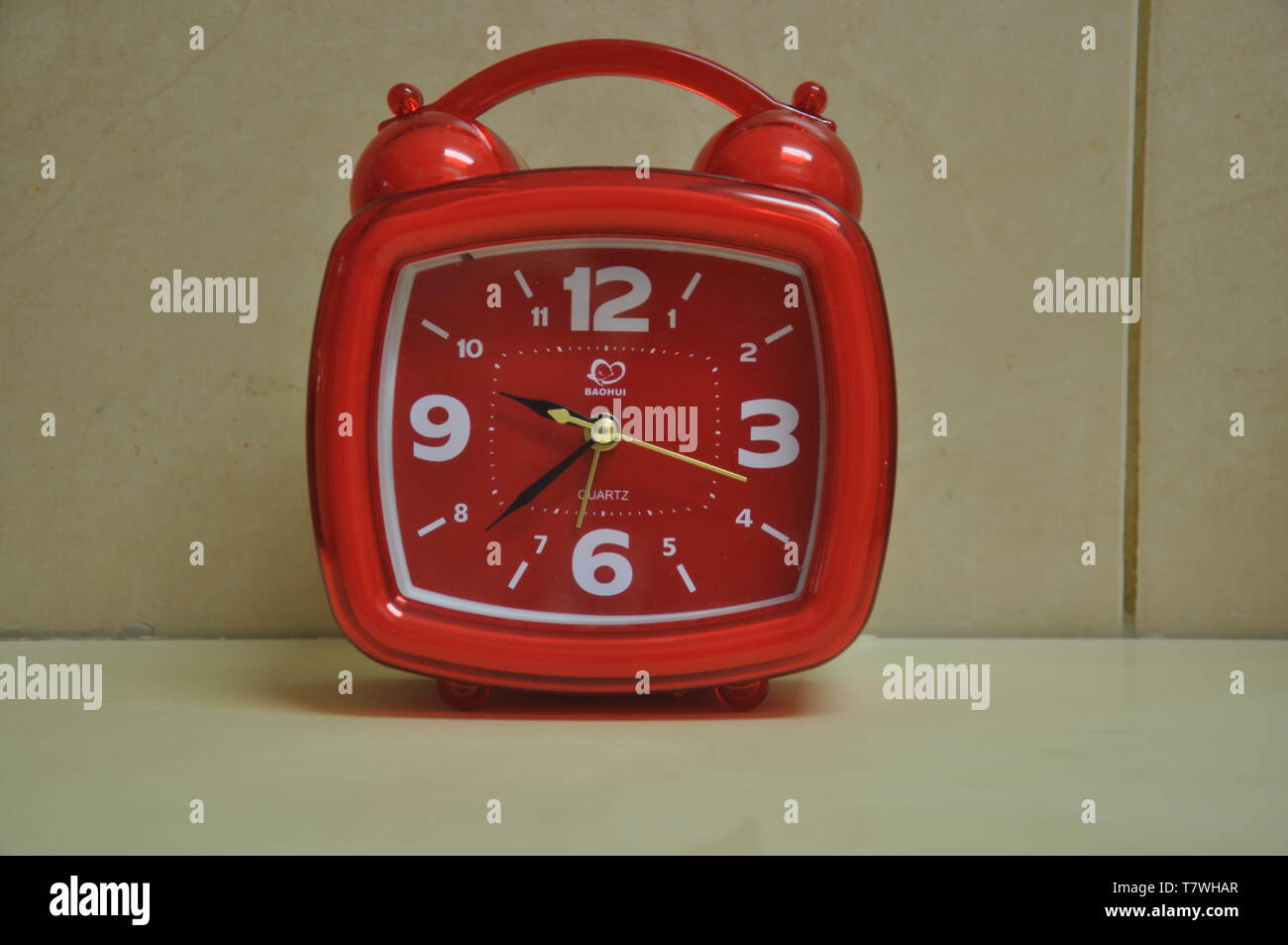 A square and red clock on the table Stock Photo