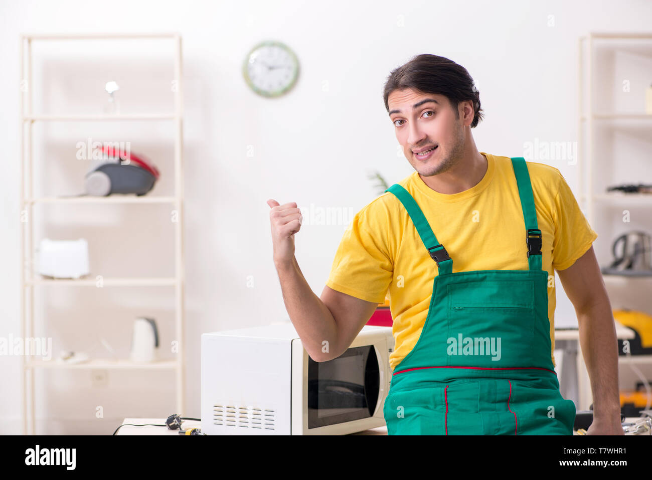 Young repairman repairing microwave in service centre Stock Photo
