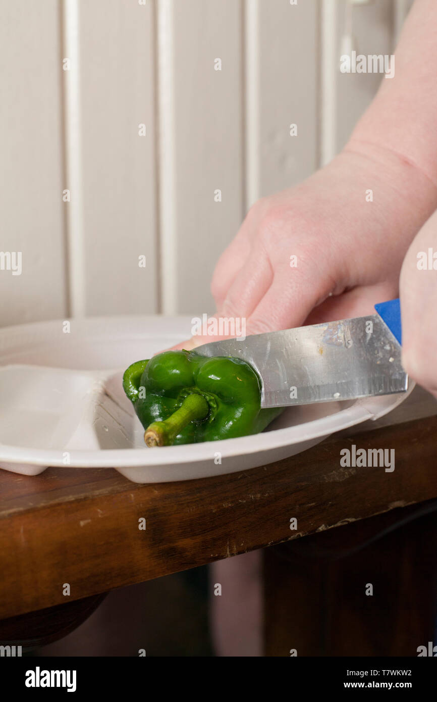 Close up of a hand chopping a green poblano pepper with a knife Stock Photo