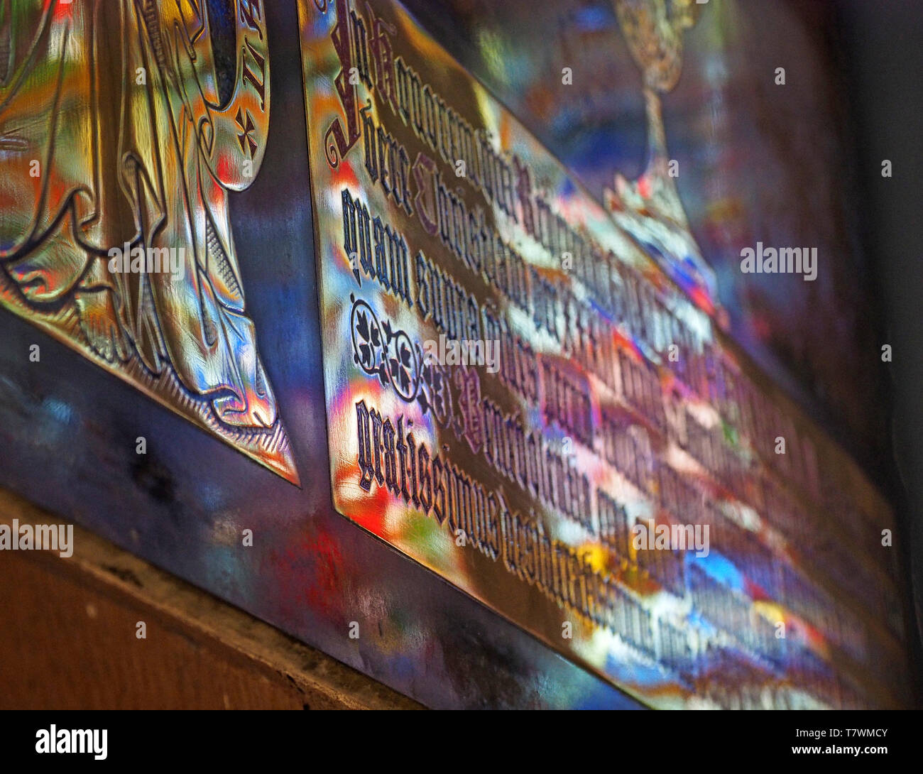 Light fantastic colours cast by sunshine through stained glass onto engraved latin