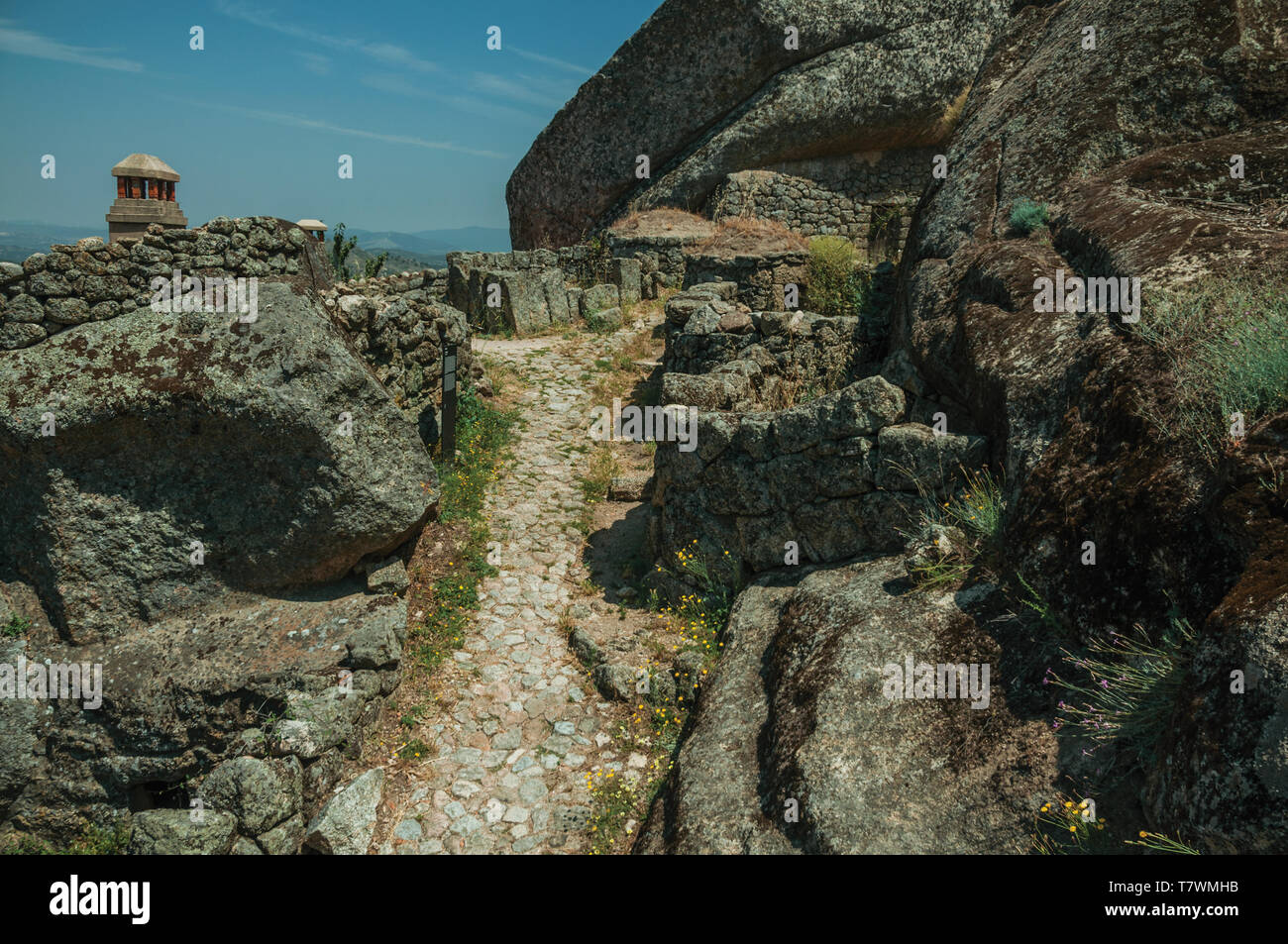 Pathway passing through big round rocks covered by moss and rough stone ...