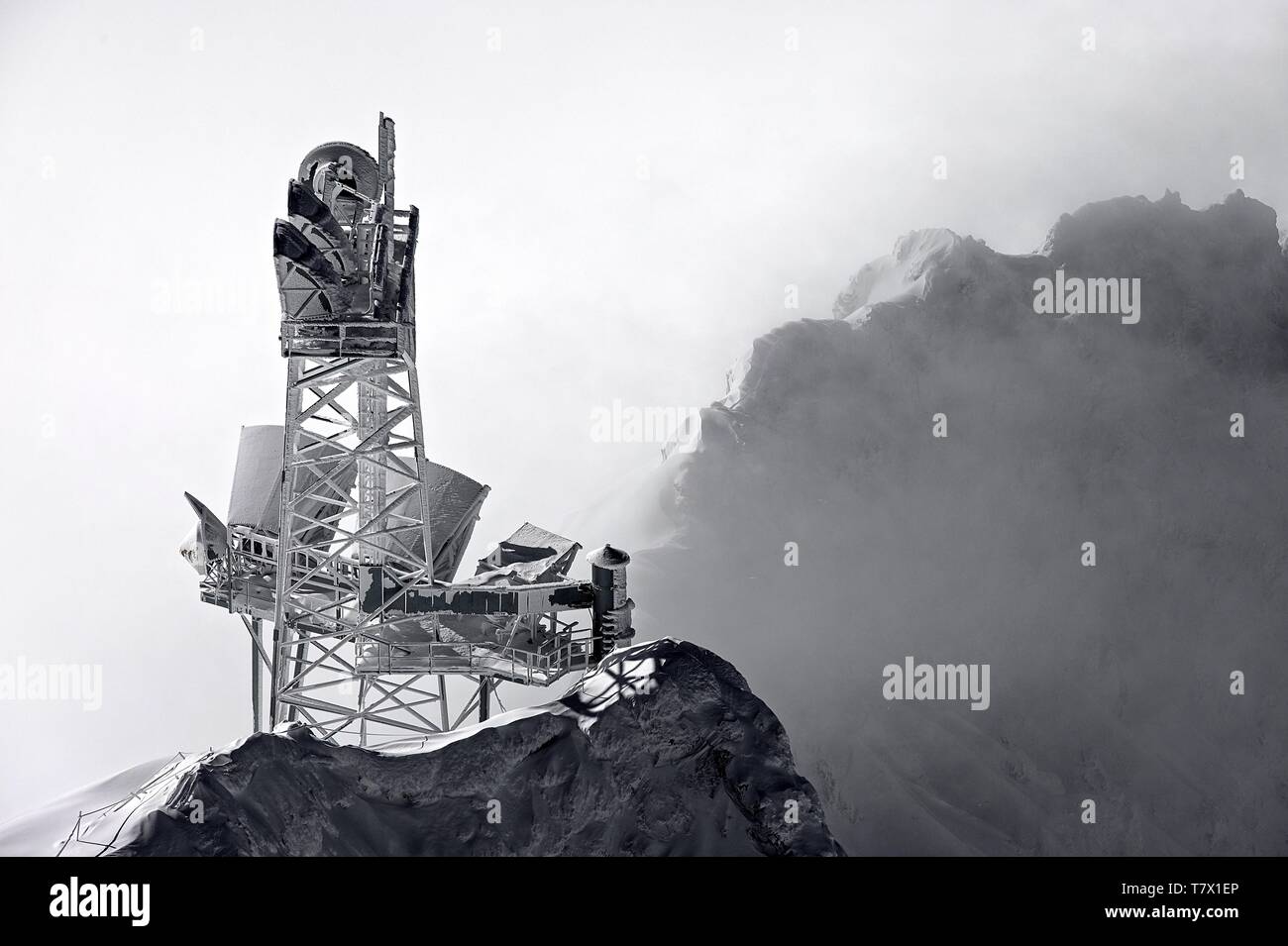 Zugspitze: Ein völlig vereister Sendemast mit vielen Schüsseln und Antennen. Er ist von dem Talnebel freigestellt Rechts ein verschneiter Berg im Nebe Stock Photo