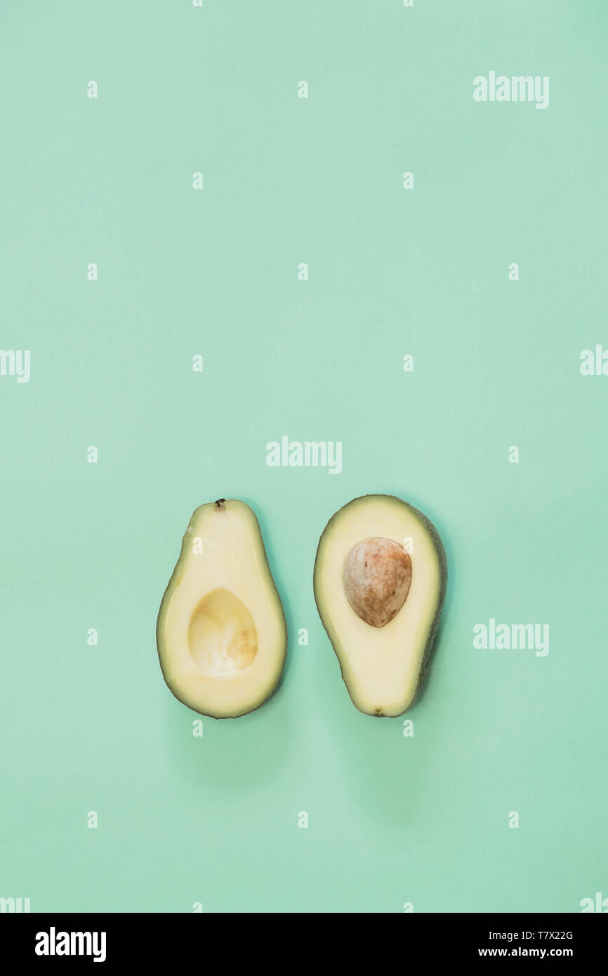 Avocado cut in half on green background  with copy space. Concept of fruitarianism, vegetarianism, veganism, natural vitamins and health. Stock Photo