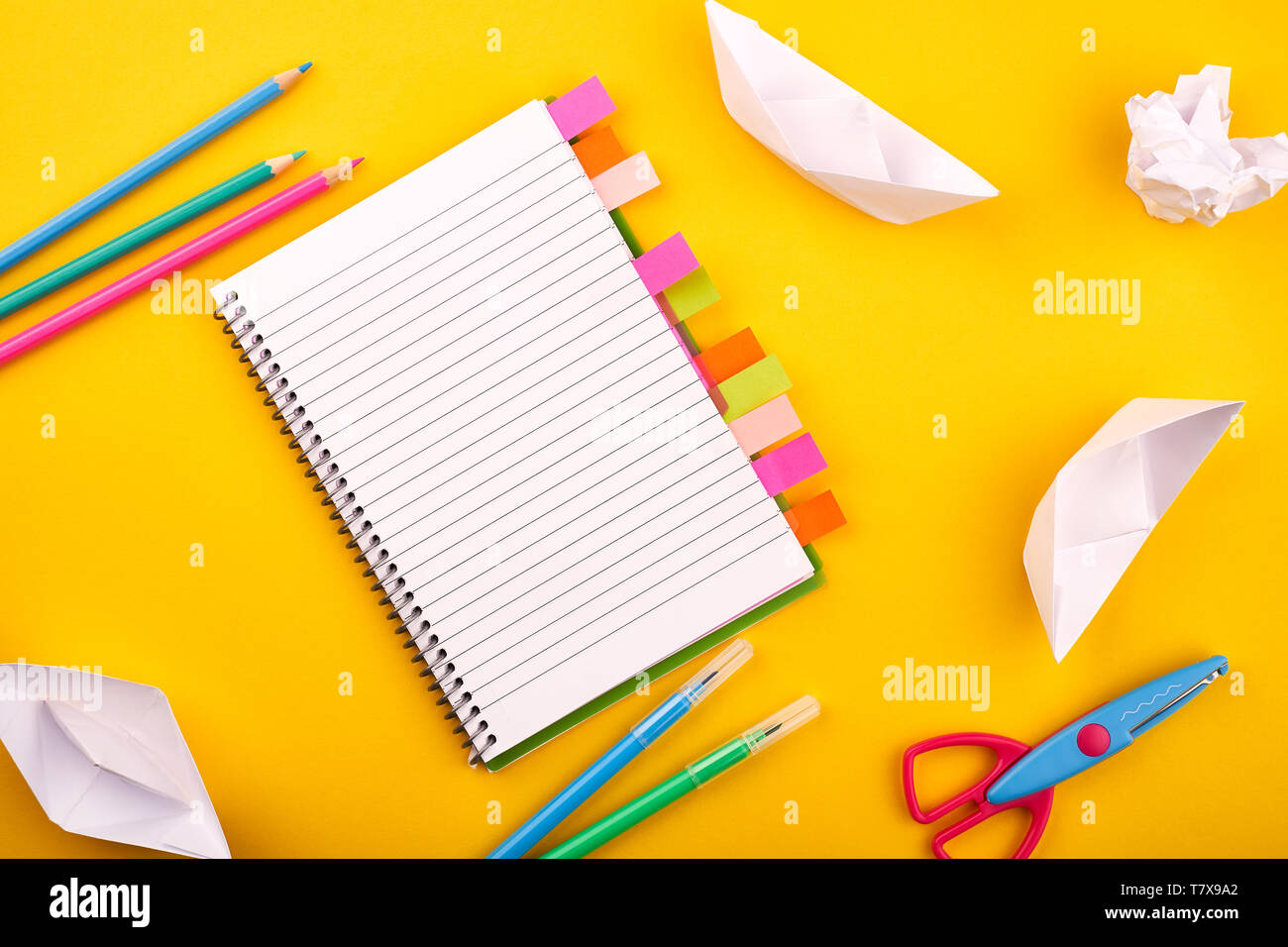 Blank white notepad with papers, pencils and scissors on yellow background Stock Photo