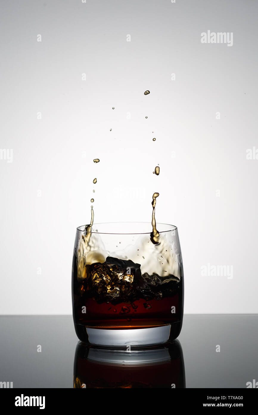 Glass of alcoholic beverage with ice on glass with reflection Stock Photo