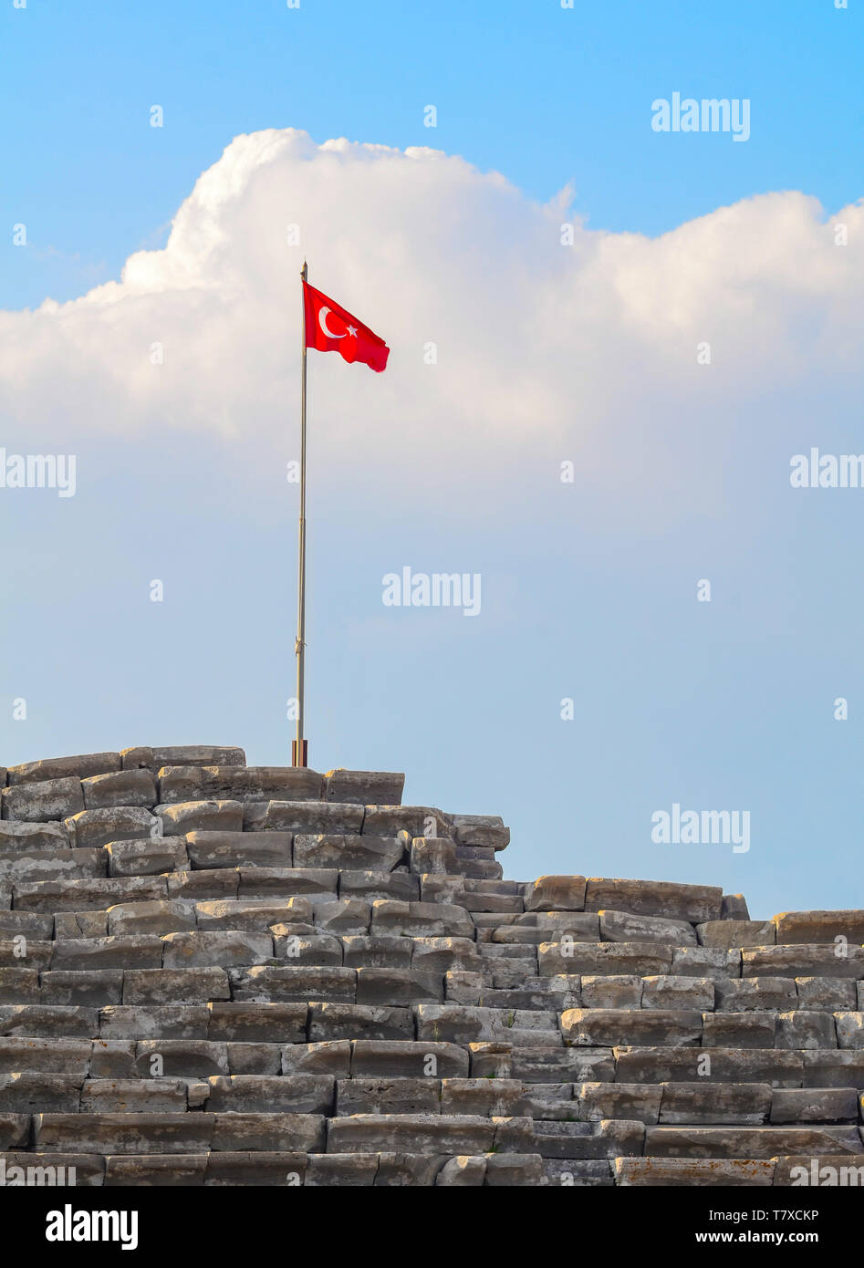 Turkish flag on top of an ancient amphitheater against the backdrop of a large cloud close-up Stock Photo