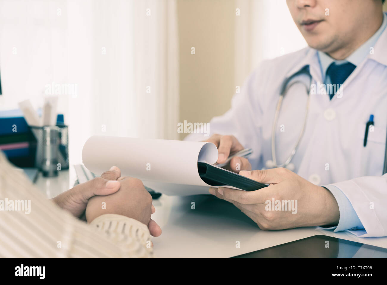 Male doctor explaining diagnosis to patient. Woman patient looking worried when listening bed news. Stock Photo