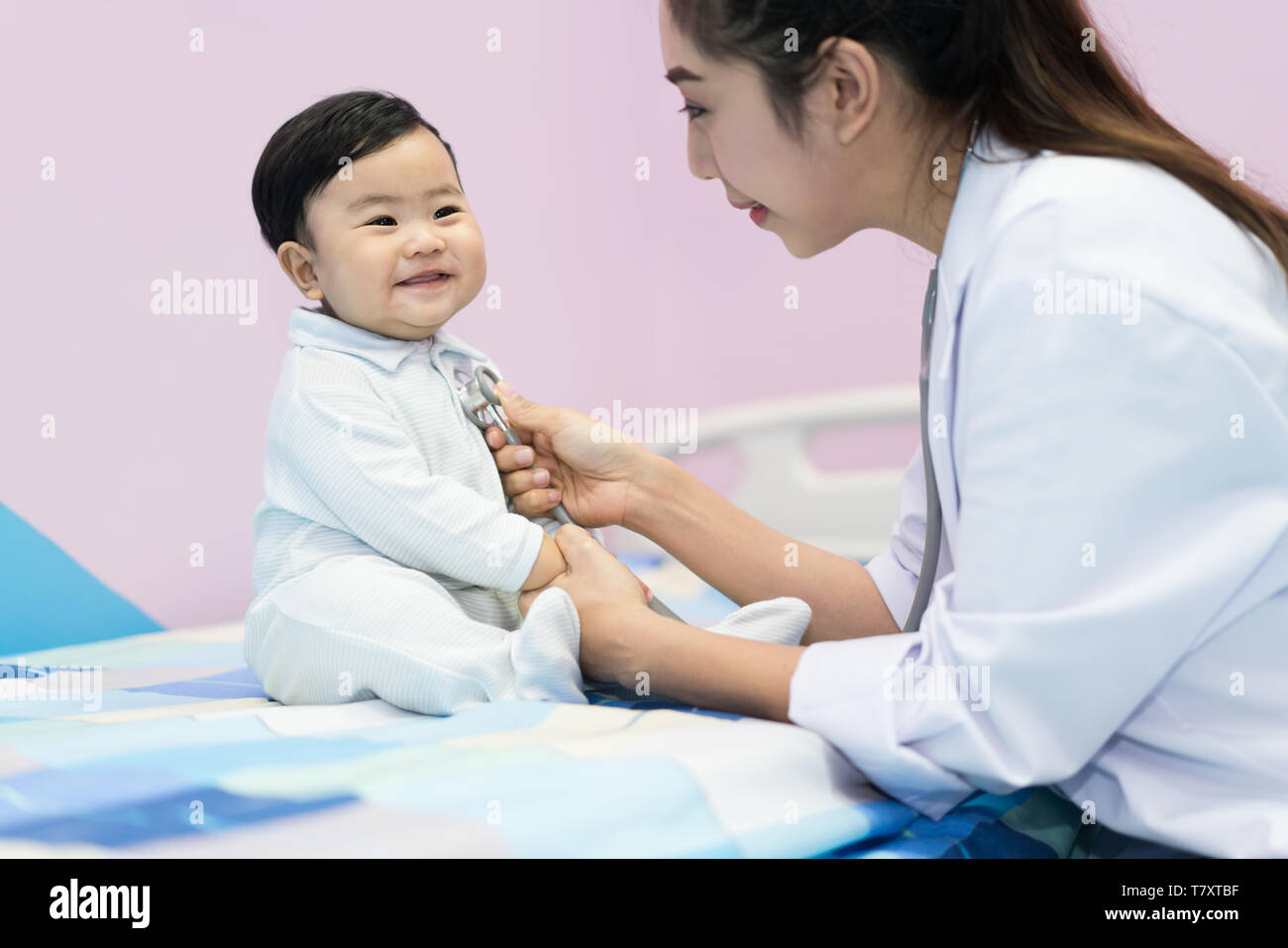 Asian doctor woman examining a little boy by stethoscope in hospital. Medicine and health care concept. Stock Photo