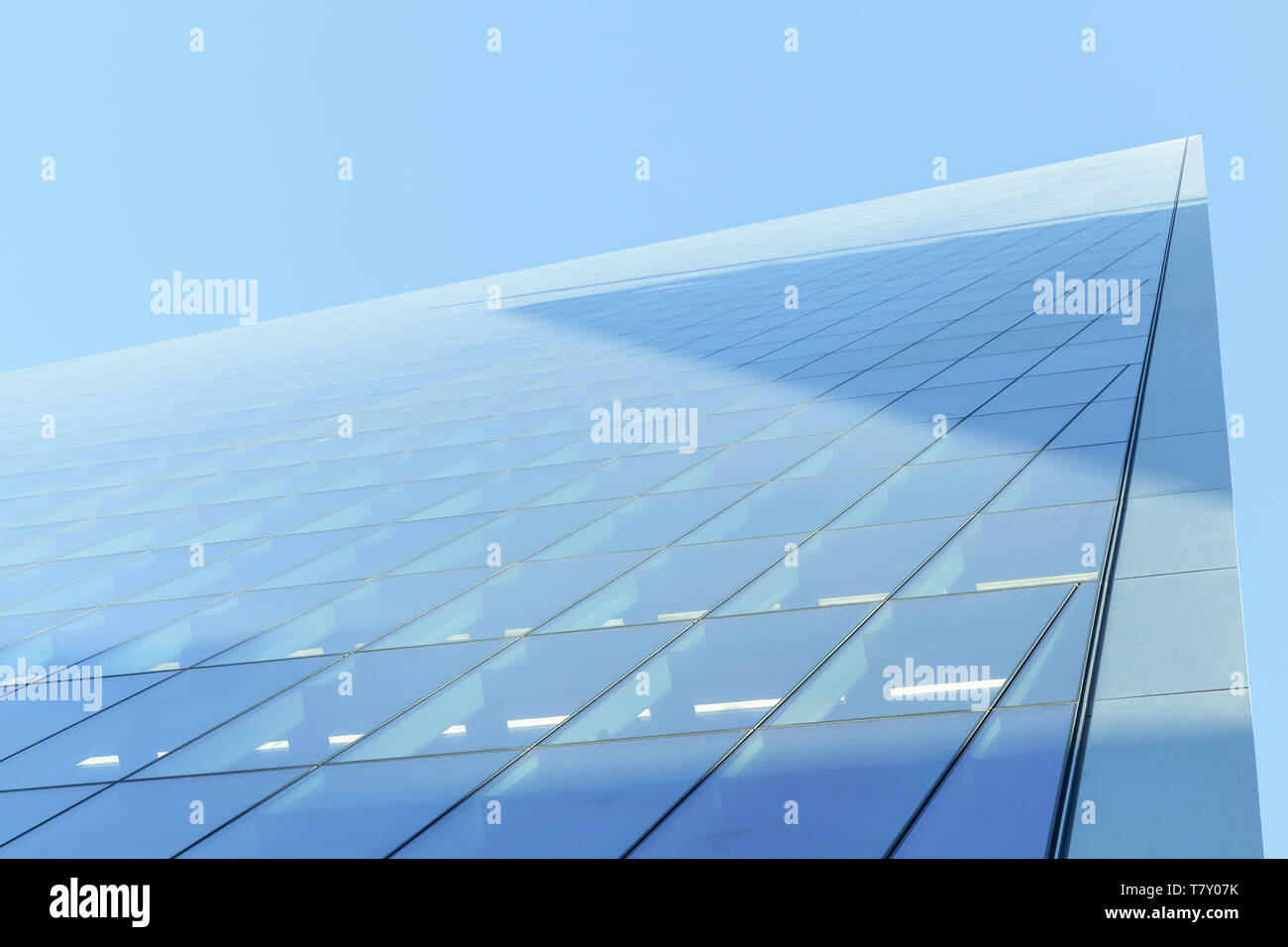 Abstract modern commercial architecture fragment, corner of walls made of shiny glass and steel under blue sky Stock Photo