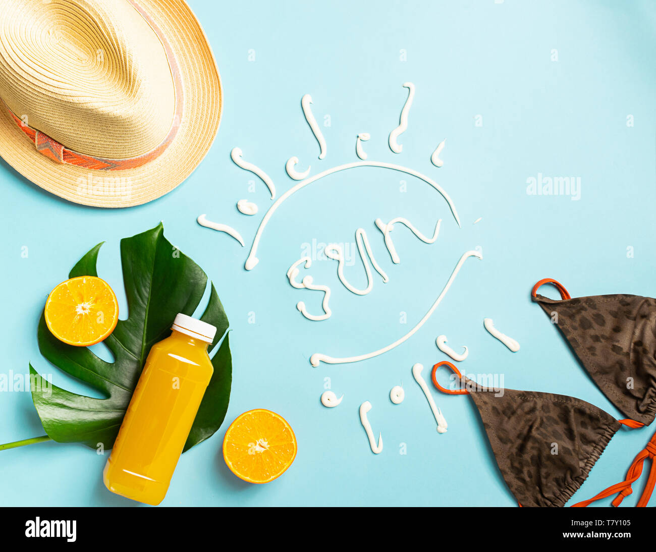 Summer beach accessories sunscreen hat bathing bottle orange juice blue background text SUN. The concept relaxation Stock Photo