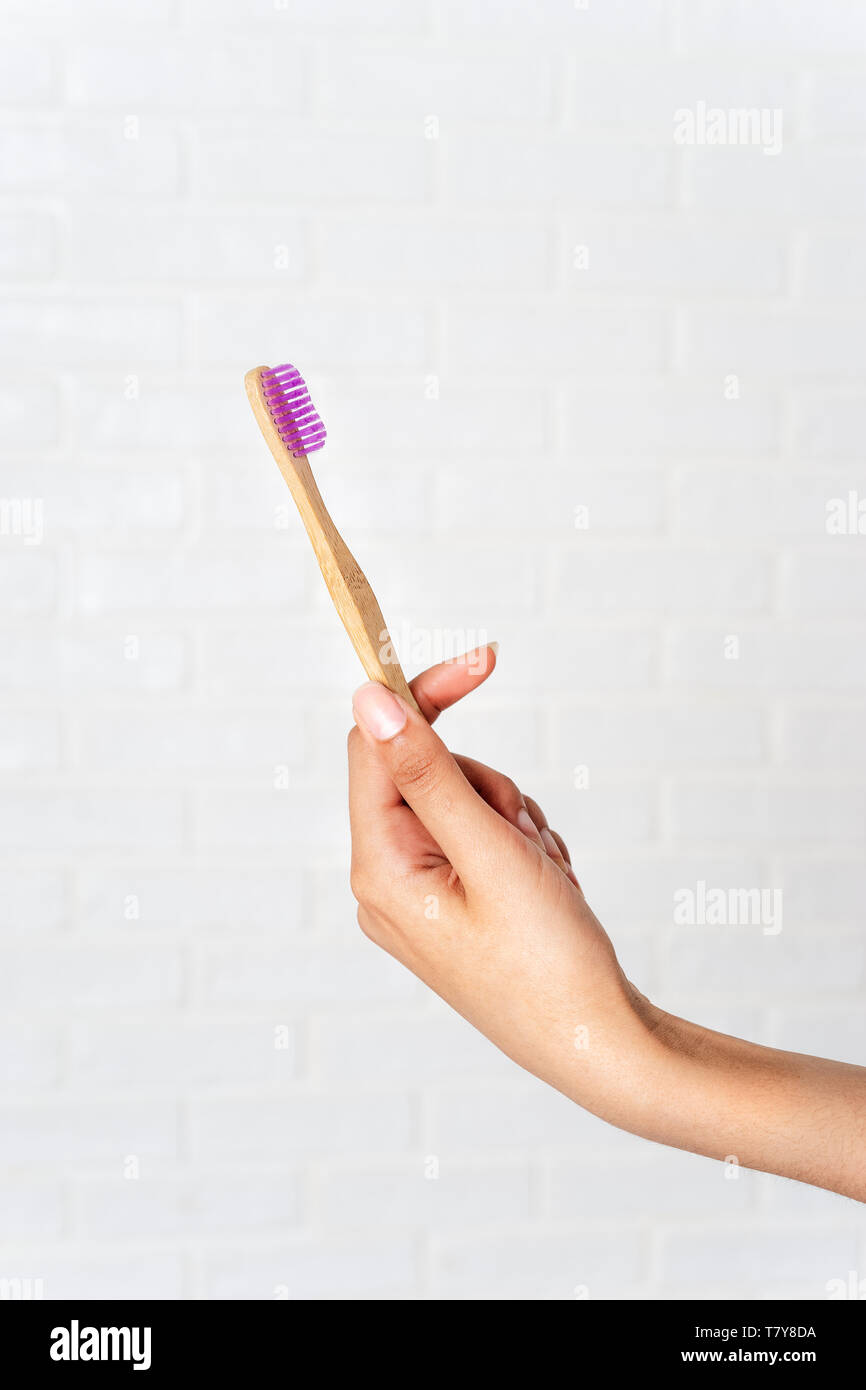 Toothbrush In Hand Close up of woman's hand holding bamboo eco toothbrush on white ...