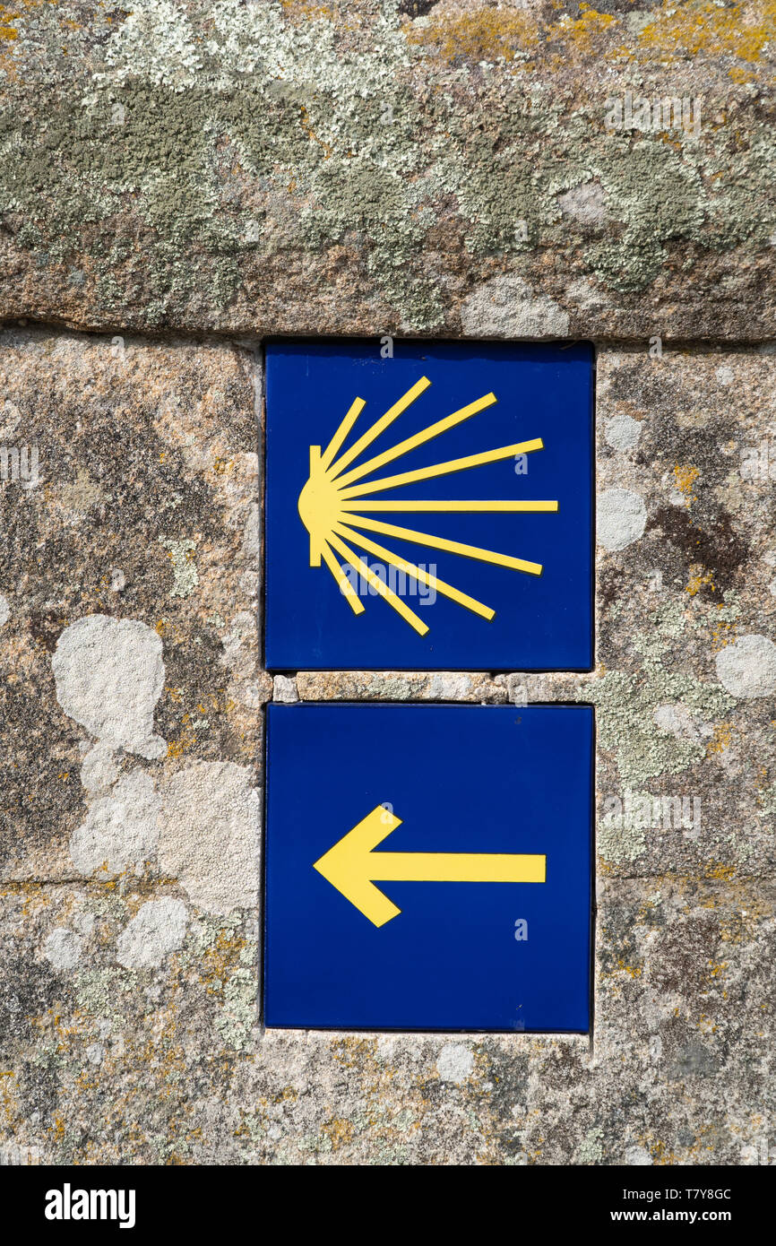 Camino de Santiago tiles on stone wall. Way of St. James signs. Arrow and shell. Santiago de Compostela Stock Photo