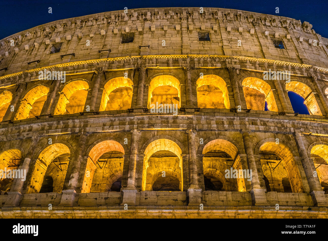 The Great Roman Colosseum and its arches at night in Rome - Italy Stock Photo