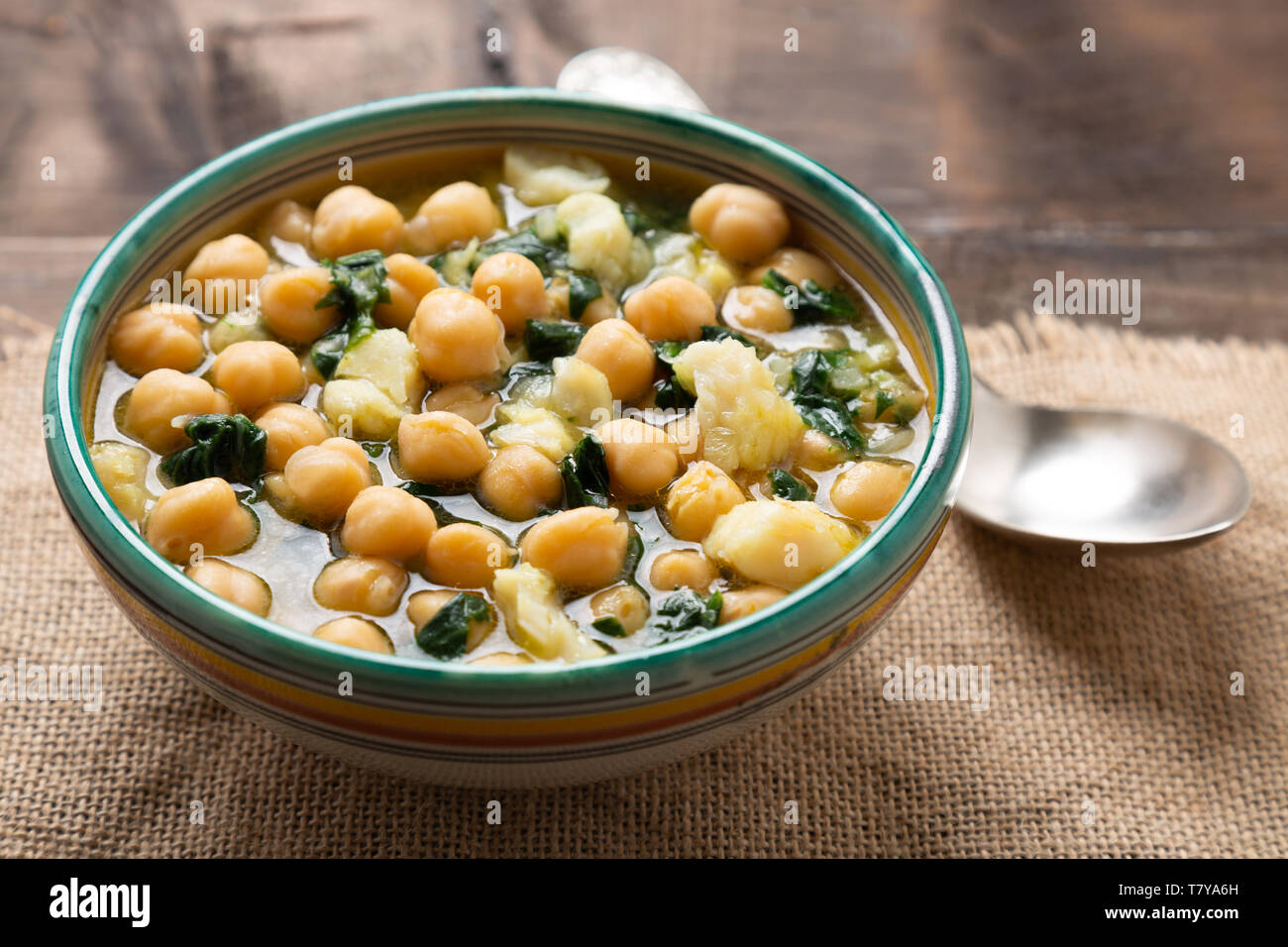 Chickpea soup with spinach and dry salted cod in a rustic bowl