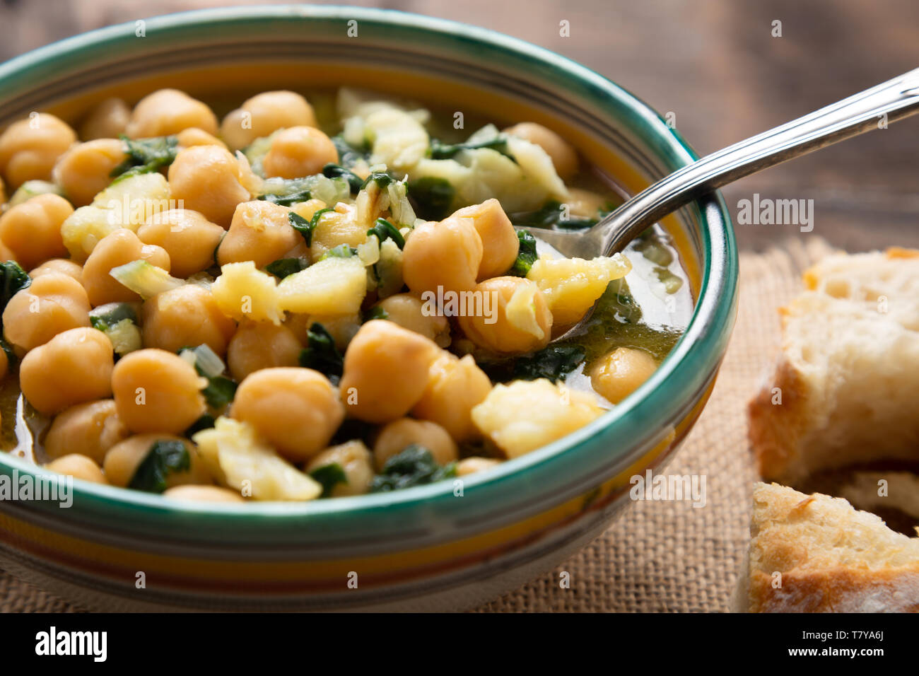 Chickpea soup with spinach and dry salted cod in a rustic bowl. Traditional spanish recipe in